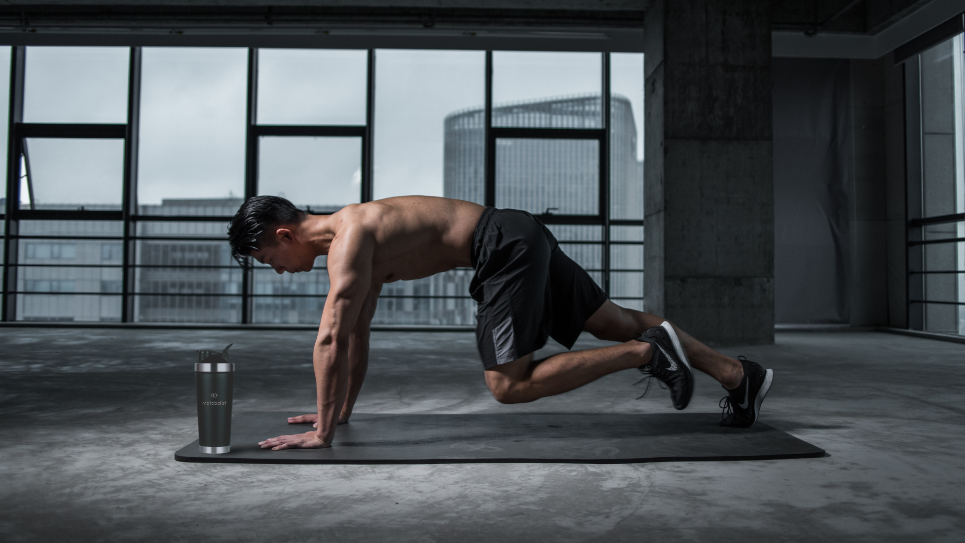 Man performing a push-up in a modern indoor setting with large windows. with Premium Stainless Steel Precision Shaker Black Bottle