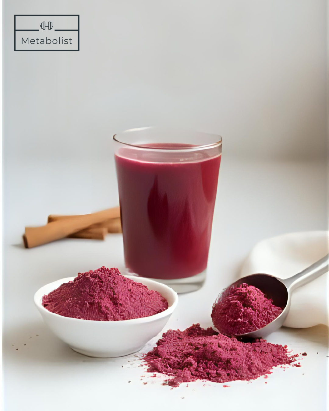 Red powder in a bowl and on a spoon with a glass of red liquid and cinnamon sticks on a light background.