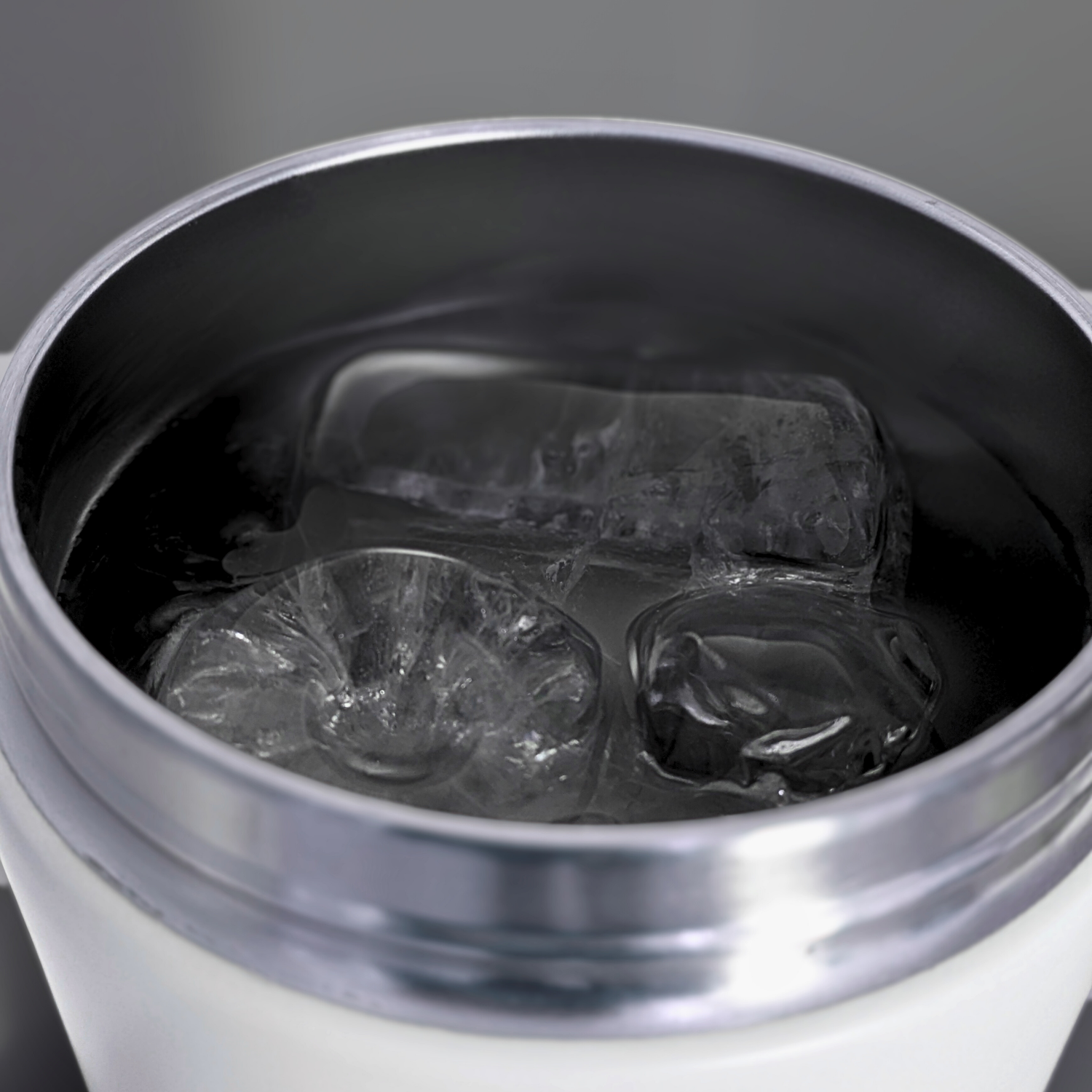 Close-up of a Metabolist Premium Stainless Steel Precision Shaker Bottle with ice cubes on a gray background.