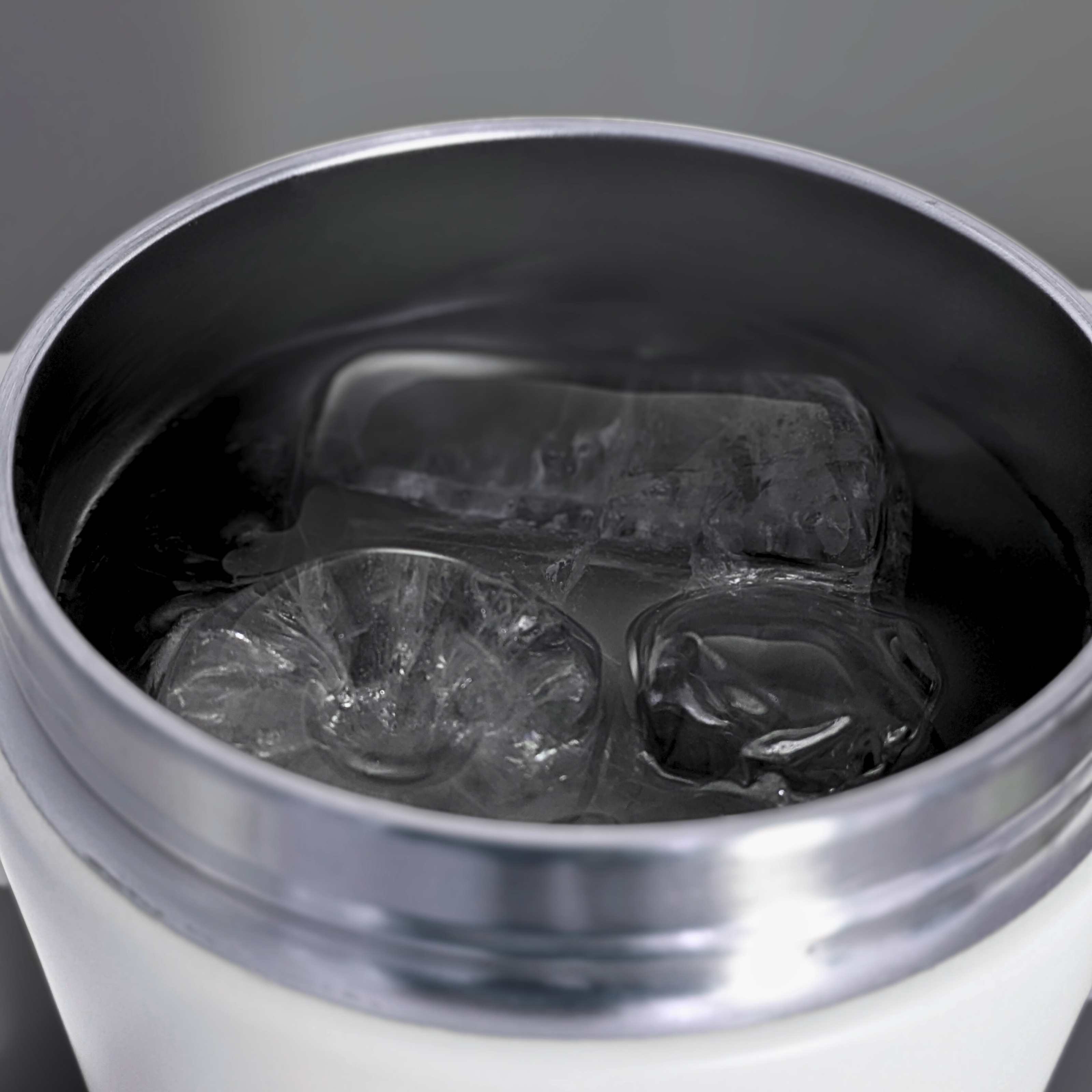 Close-up of a Metabolist Premium Stainless Steel Precision Shaker Bottle with ice cubes on a gray background.