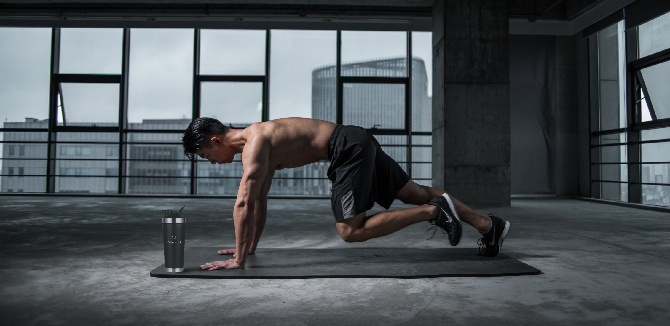 Man performing a push-up in a modern indoor setting with large windows. with Premium Stainless Steel Precision Shaker Black Bottle