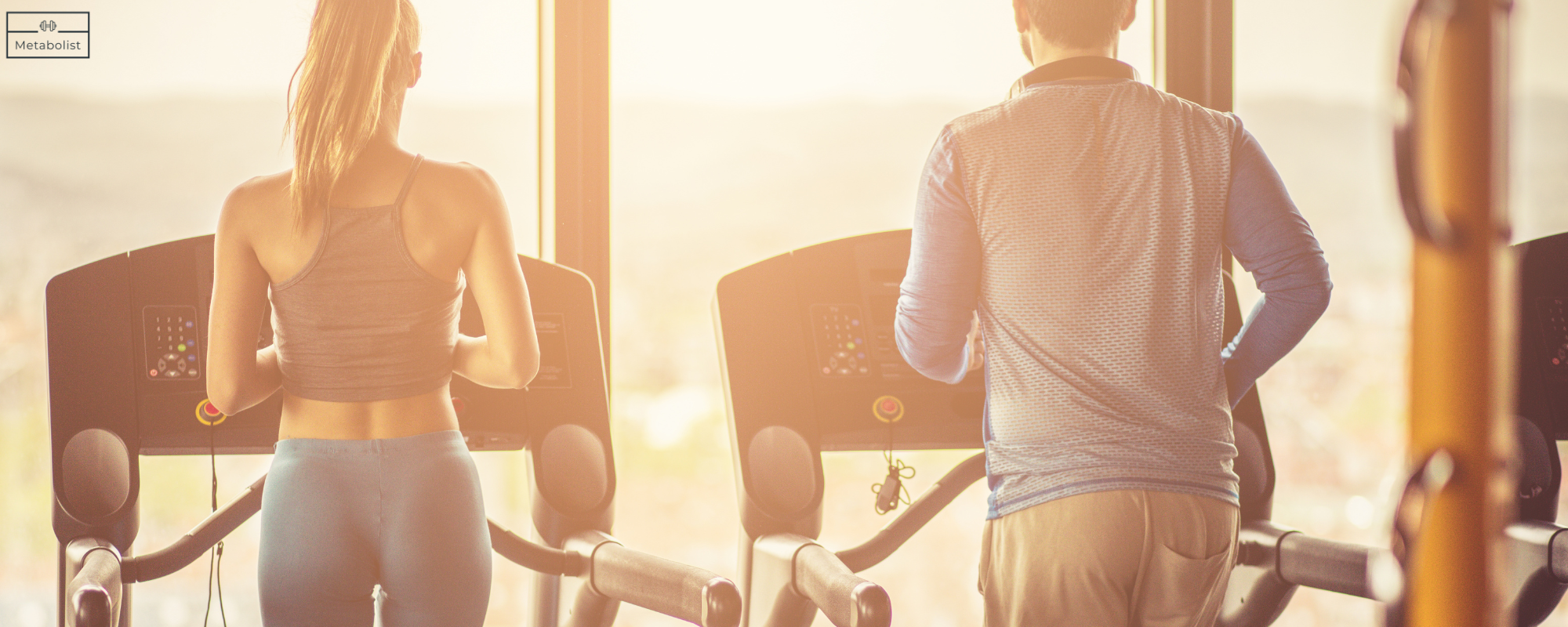 Two people on treadmills in a gym with a warm, golden light.