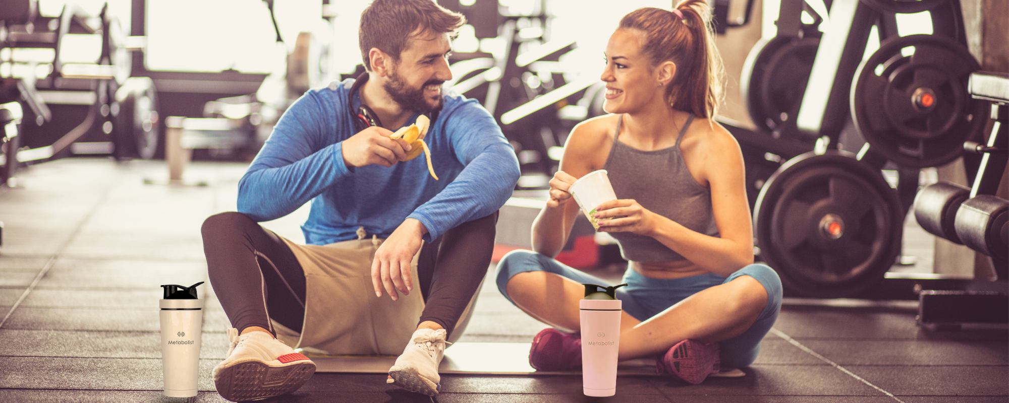 Two people sitting on a mat in a gym, eating snacks with Premium Stainless Steel Precision Shaker Bottle