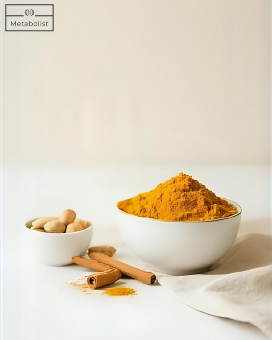 Turmeric powder in a white bowl with cinnamon sticks and whole turmeric roots on a light background.