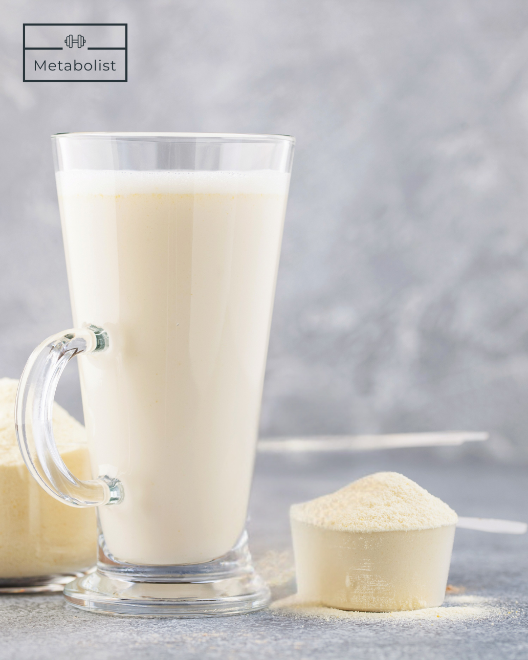Glass of milk with a scoop of protein powder on a gray background, featuring the 'Metabolist' brand.