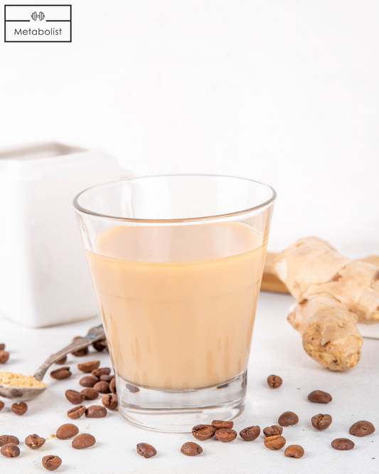 Glass of creamy beverage with ginger root and coffee beans on a white background